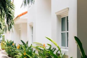 a white building with plants in front of it at Talay Hotel and Villa Cha-am in Cha Am