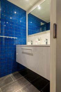 達默的住宿－De gouden Kop 2 Vakantiestudio Centrum Damme，蓝色瓷砖浴室设有水槽和镜子