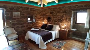 Un dormitorio con una cama y una pared de piedra. en Casa A Chairiña y A Revolta, en Arnoia