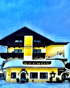 un bâtiment jaune avec un panneau dans la neige dans l'établissement Appartementhaus Seehof, à Kirchberg in Tirol