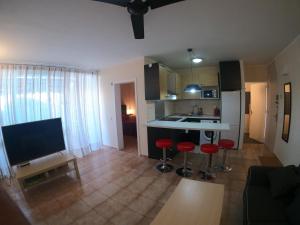 kuchnia i salon z czerwonymi stołkami w pokoju w obiekcie Apartamento Primavera Costa del Silencio w mieście Costa Del Silencio