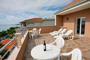 patio z białymi krzesłami i stołem z butelką wina w obiekcie Dalmacija w Omišu