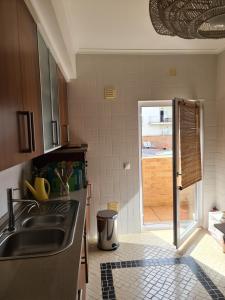 a kitchen with a sink and a door to a patio at Pé na Praia da Foz in Foz do Arelho