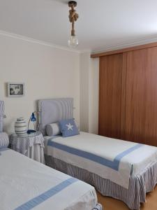 a bedroom with two beds and a wooden wall at Pé na Praia da Foz in Foz do Arelho