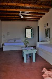 a bedroom with two beds and a table and a bed at Pambelos Lodge in Koufonisia