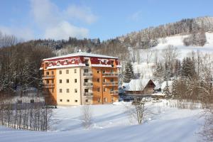 a large building in the snow with snow covered ground at Apartmán Škrovanová in Ober Lindewiese