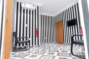 a hallway with two chairs and a fire hydrant on a striped wall at Covenant Hotel in Accra