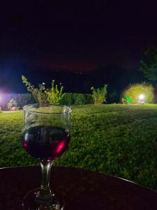 a glass of wine sitting on a table at night at Artolithia Apartments in Rizá