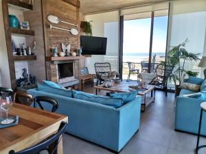 una sala de estar con sofás azules y vistas al océano. en Casa Punta lobos - Pichilemu. A pasos de la playa condominio privado, en Pichilemu