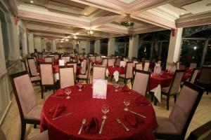 Imperial Holiday Hôtel & spa في مراكش: قاعة احتفالات بمناضد حمراء وكراسي مع كؤوس للنبيذ