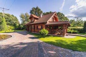 a small wooden house with a brick driveway at Woodhouse in Łubowo