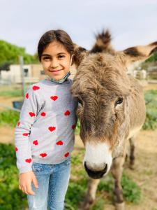 Ein kleines Mädchen steht neben einer Kuh in der Unterkunft ASINERIE KULENI in Ponteilla