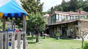 uma casa com uma cerca de madeira e um parque infantil em Casa A Chairiña y A Revolta em Arnoia