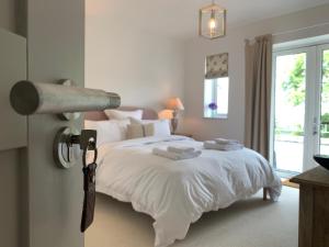 a bedroom with a large white bed with a lamp at The Gate Cornwall in Looe