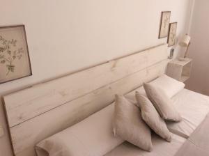 a white bedroom with a wooden headboard and pillows at Villa Martí in Calpe