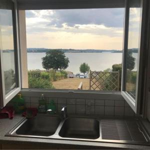 a kitchen sink with a window looking out at the water at Maison bord de Lac de Pareloup in Salles-Curan