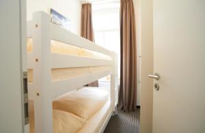 ein weißes Etagenbett in einem Zimmer mit Fenster in der Unterkunft Apartment Eisberg 3 mit schöner Balkonterrasse in Norderney
