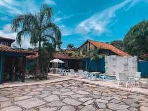 un patio con sillas blancas y una palmera en Recanto Al Mare, en Búzios