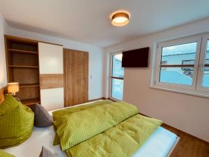 sypialnia z zielonym łóżkiem i oknem w obiekcie Gästehaus Lehner-Au w Langenfeld