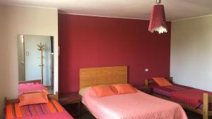 1 Schlafzimmer mit 2 Betten und einer roten Wand in der Unterkunft Habitaciones en Buena Vista in Lima