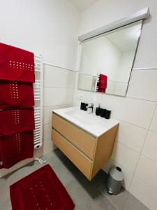 W łazience znajduje się umywalka, lustro i czerwone ręczniki. w obiekcie Gästehaus Lehner-Au w Langenfeld