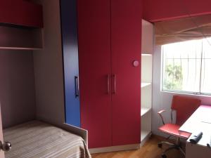 1 dormitorio con armarios rojos, 1 cama y escritorio en Habitaciones en Buena Vista, en Lima