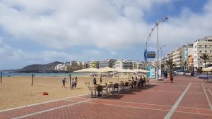 ein Strand mit Stühlen und Sonnenschirmen und Menschen am Strand in der Unterkunft Apartamento Hierro 21-2 in Las Palmas de Gran Canaria