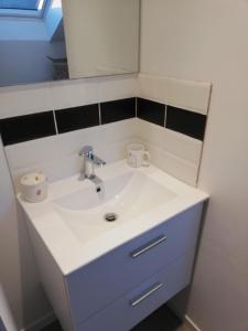 W łazience znajduje się biała umywalka i lustro. w obiekcie Au cochon qui rit w mieście Flines-lès-Mortagne