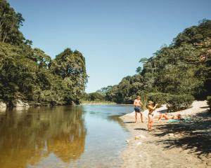 a group of people walking on a beach next to a river at Rio Hostel Buritaca in Buritaca