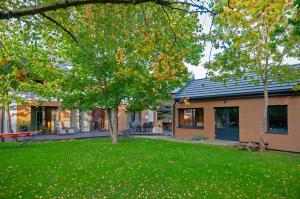 ein Haus mit einem grünen Garten mit einem Baum in der Unterkunft Wiselka Holiday House-1,2km to the beach; 5 bedrooms, 3 bahrooms; fire place. Private sauna! in Wisełka