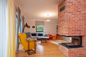 ein Wohnzimmer mit gemauertem Kamin und gelben Stühlen in der Unterkunft Wiselka Holiday House-1,2km to the beach; 5 bedrooms, 3 bahrooms; fire place. Private sauna! in Wisełka