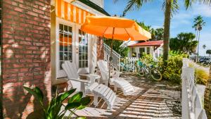 a patio with white chairs and an orange umbrella at Coconut Inn Pass-a-Grille Beach in St Pete Beach