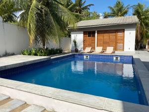 Casa Mundaú Tropical Beach Villa في مونداو: مسبح وكراسي ومنزل