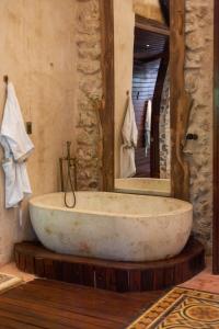 a large stone tub in a bathroom with a mirror at La Casa del Encomendero in Valladolid