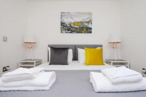Schlafzimmer mit einem Bett mit weißer Bettwäsche und gelben Kissen in der Unterkunft The Zone - Vibrant City Centre Apartment in Nottingham