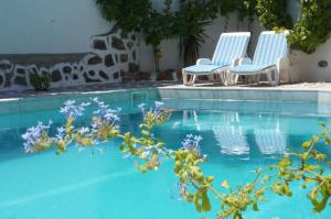 duas cadeiras sentadas ao lado de uma piscina em Captain's House Hotel em Skala