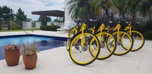 a row of yellow bikes parked next to a pool at Atlantida Park Residence in Xangri-lá