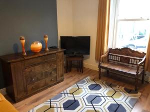 a living room with a tv and a wooden dresser at Mariyka House in Torquay