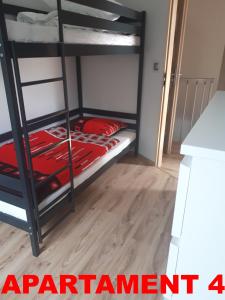a room with two bunk beds with red sheets at KOPALINO Apartamenty nad morzem in Kopalino