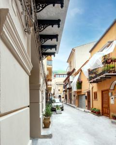an alley in a town with cars parked on the street at Palazzo al Carmine in Monreale