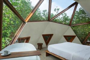 a bedroom with a bed, a chair and a window at Mamasan Treehouses & Cabins in Tulum
