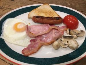 um prato de comida com ovos, bacon, salsicha e cogumelos em Highland Moors em Llandrindod Wells