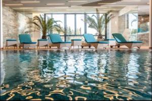 una piscina con sedie blu e acqua in un edificio di Luxury Silver Mountain Apartment a Poiana Brasov