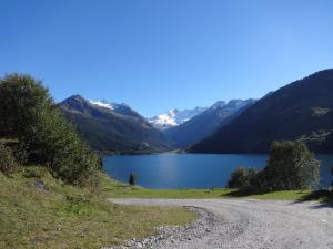 un camino de tierra junto a un lago con montañas en Berghotel Der Königsleitner - Adults only en Königsleiten