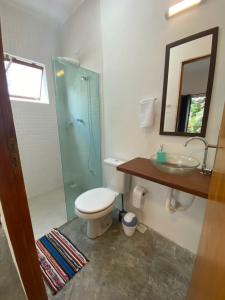 uma casa de banho com um WC, um lavatório e um espelho. em Casa Praiana no Guarujá