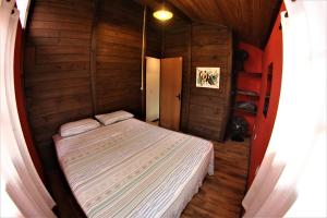 a small bedroom with a bed in a wooden room at Casa inteira sozinha no pátio com estacionamento - Guarda do Embaú in Guarda do Embaú