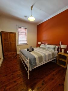 a bedroom with a bed with a wooden wall at Arden on McLachlan in Orange