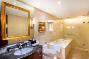 a bathroom with a tub and a toilet and a sink at Golden Ocean Hotel Tianjin in Tianjin