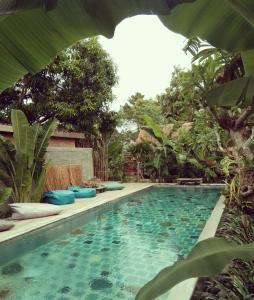 una piscina en medio de un jardín en Wooden house at Semadi living en Sukawati