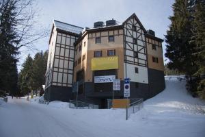 a building on a snow covered street in front of a building at Apartmán u sjezdovky Javor in Pec pod Sněžkou